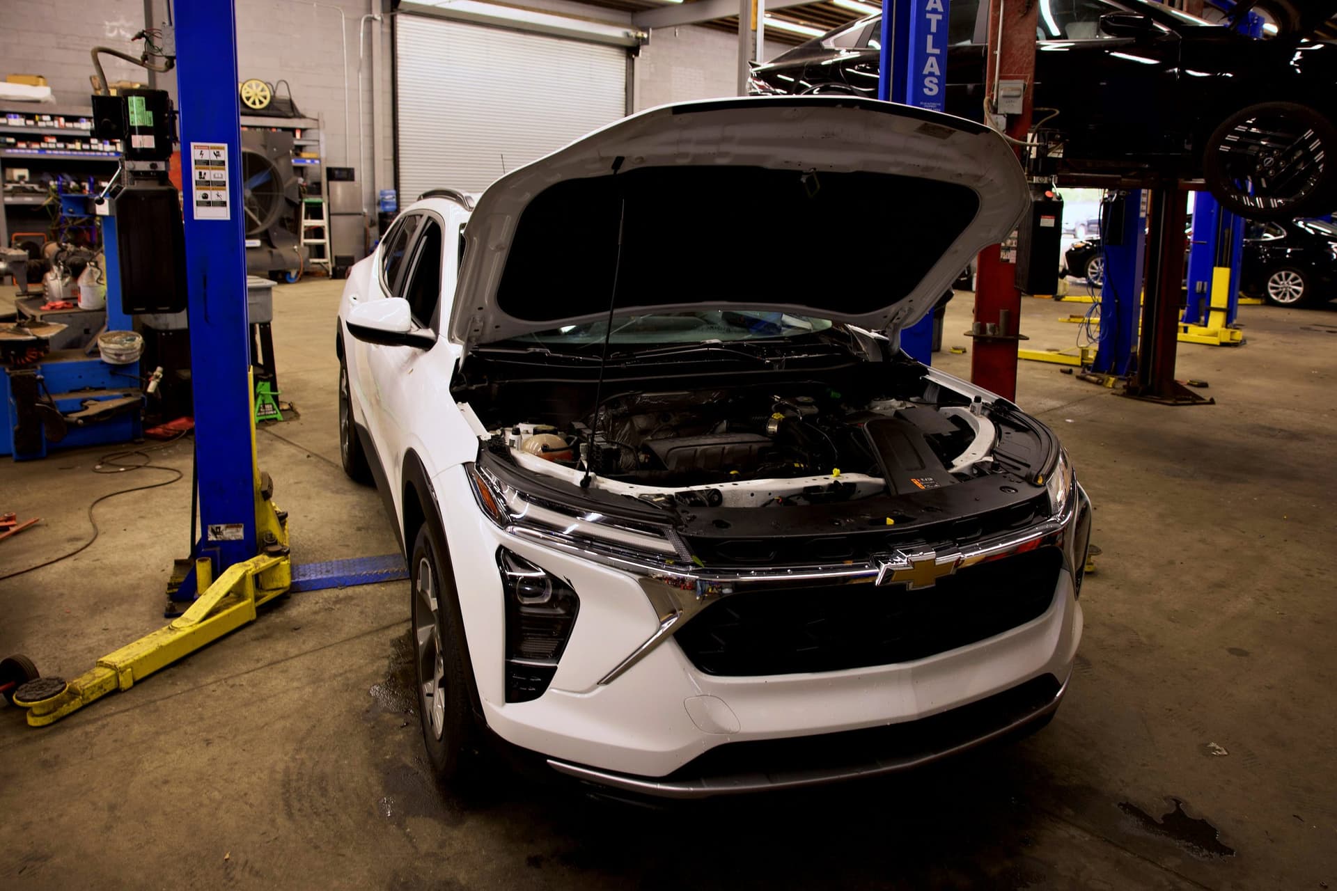 A white Chevrolet SUV with the hood open in a Newark service bay