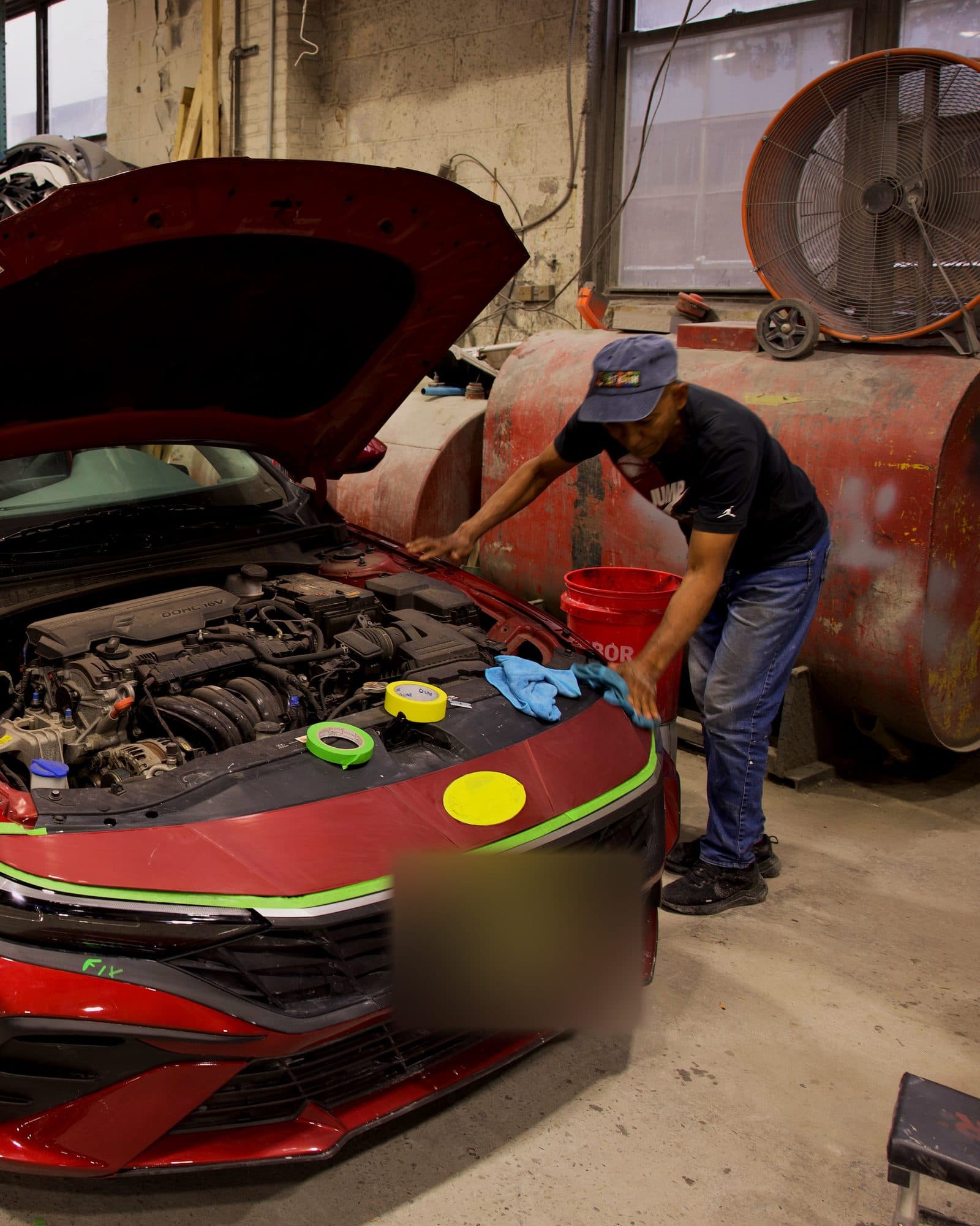 A Car2Fix technician cleaning a red Hyundai before paint at the Linden shop