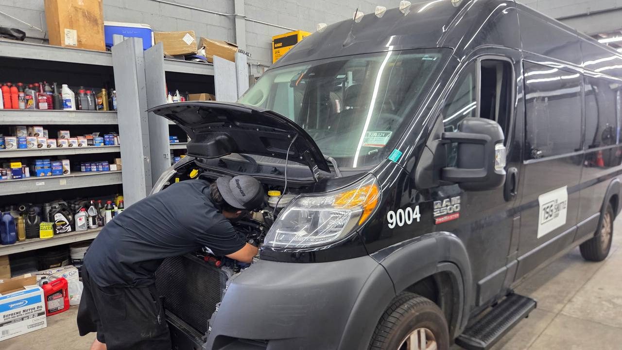 A technician working under the hood of a Shuttle Group ProMaster
